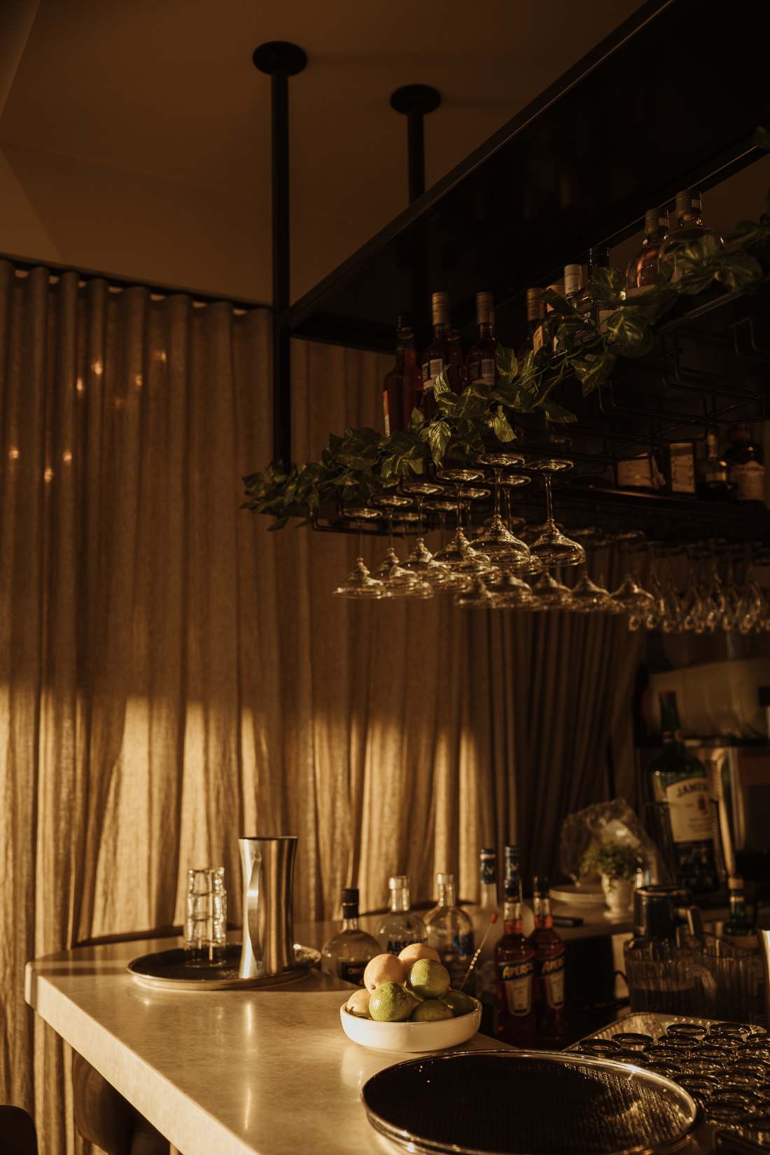 The Gio's bar in warm evening light, with hanging glasses and bottles
