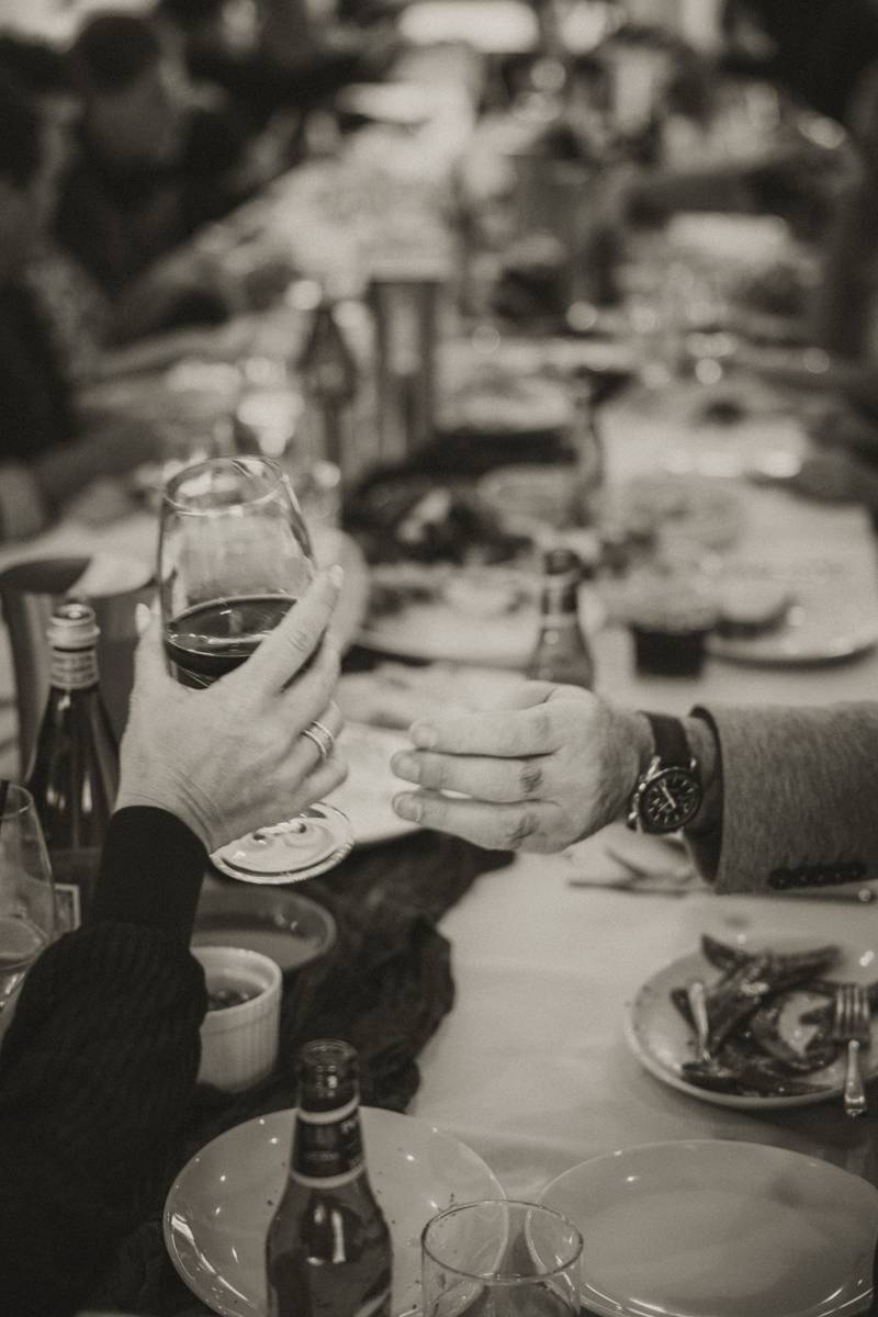 Two guests raising a glass in a toast across a long dining table